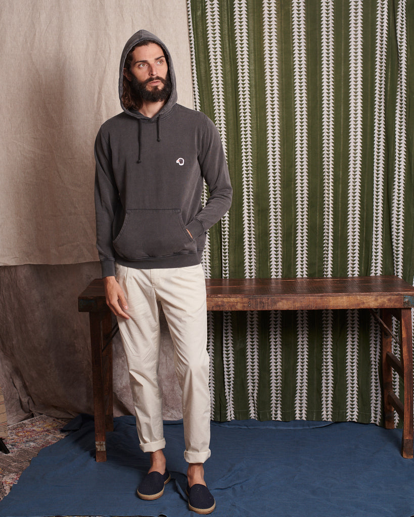 Sudadera de corte unisex con capucha reforzada y bolsillo de canguro.   Detalle de ojales en la capucha con cordón marinero y nuestro cuervo insignia en el pecho.   Diseñada en España Confeccionada en Portugal con algodón 100% orgánico Tinte ecológico Puños y bajos en ribete elástico Disponible en más colores.   Diego mide 188cm y lleva una talla L